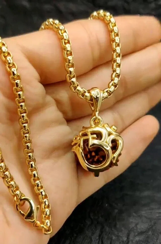 Gold necklace with a pendant held in a hand against a dark background
