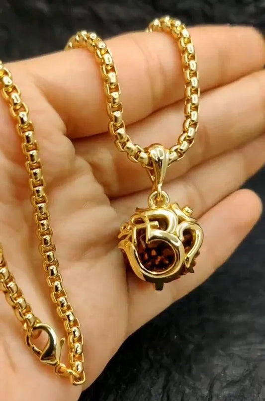 Gold necklace with a pendant held in a hand against a dark background